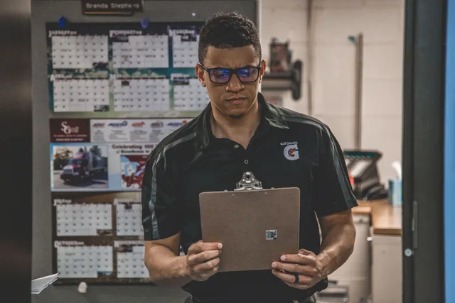 A serious worker in a warehouse checks documents on a clipboard, planning and logistics. Water restoration service standards: the eight documents a crew will actually use