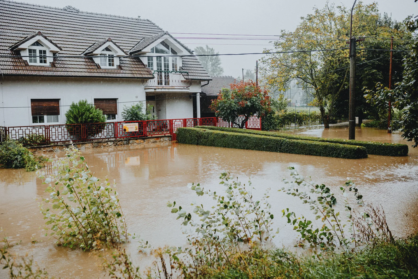 A suburban house surrounded by floodwaters after heavy rain, showing impact of natural disaster. Water restoration customer acquisition: calls and follow-up