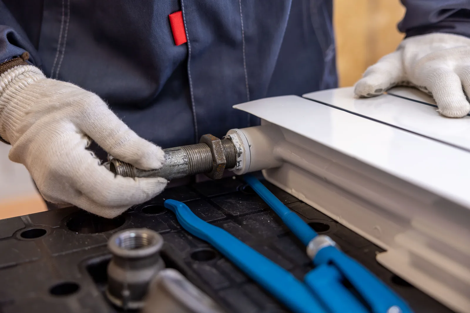 Close-up of a plumber installing a radiator pipe using specialized tools. Getting more water restoration owners referrals without begging