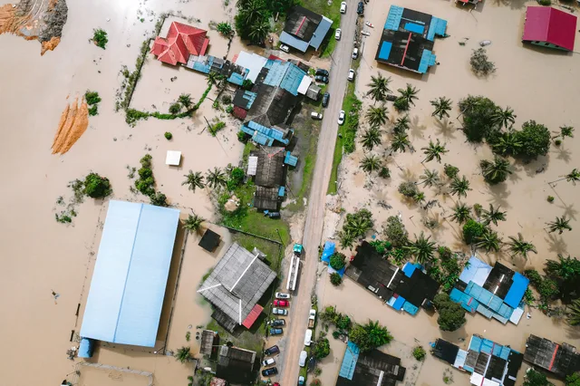 Drone view of a residential area in Kijal, Malaysia, showing extensive flooding and submerged buildings. Water restoration employee pay: a labor-cost framework