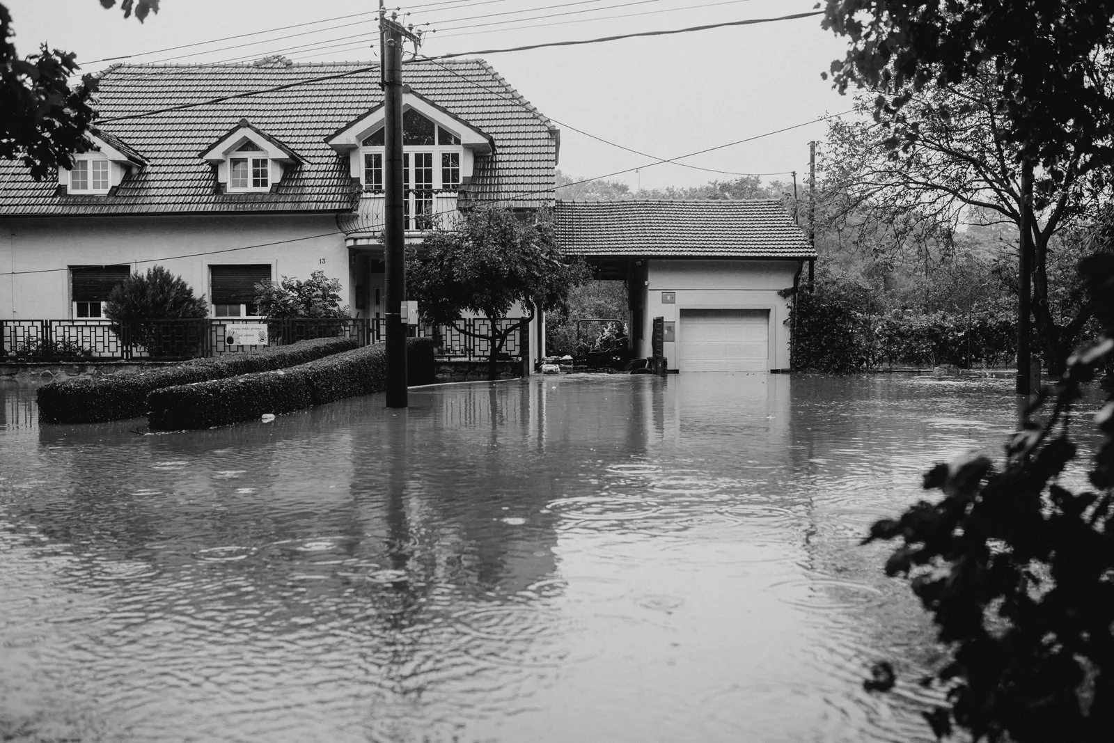 A flooded suburban house surrounded by high water, depicting severe weather impact. Water restoration startup: lanes, license and demand